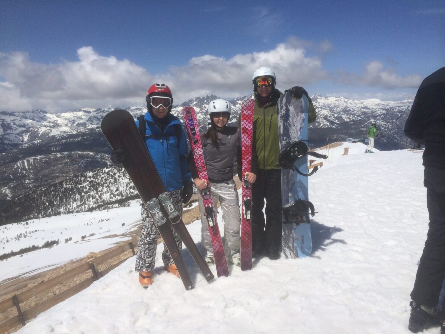 three people holding monoski, snow skis, and snowboard